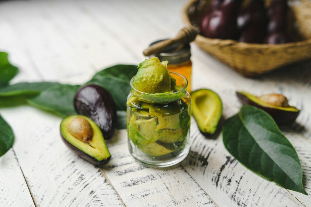Sliced avocado beside a glass bottle of cooking oil
