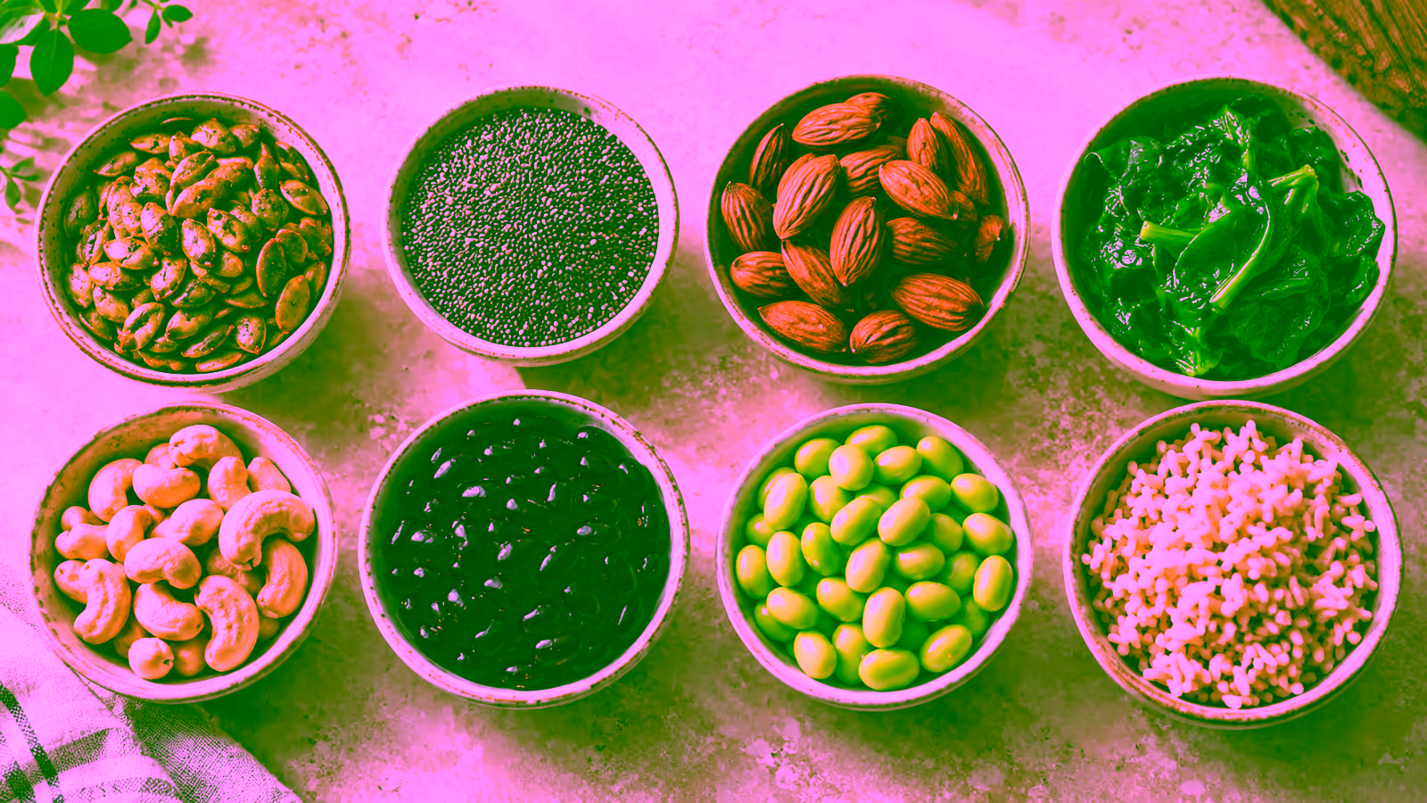 Pumpkin seeds, almonds, black beans, spinach, brown rice, chia seeds, and edamame arranged as magnesium-rich foods