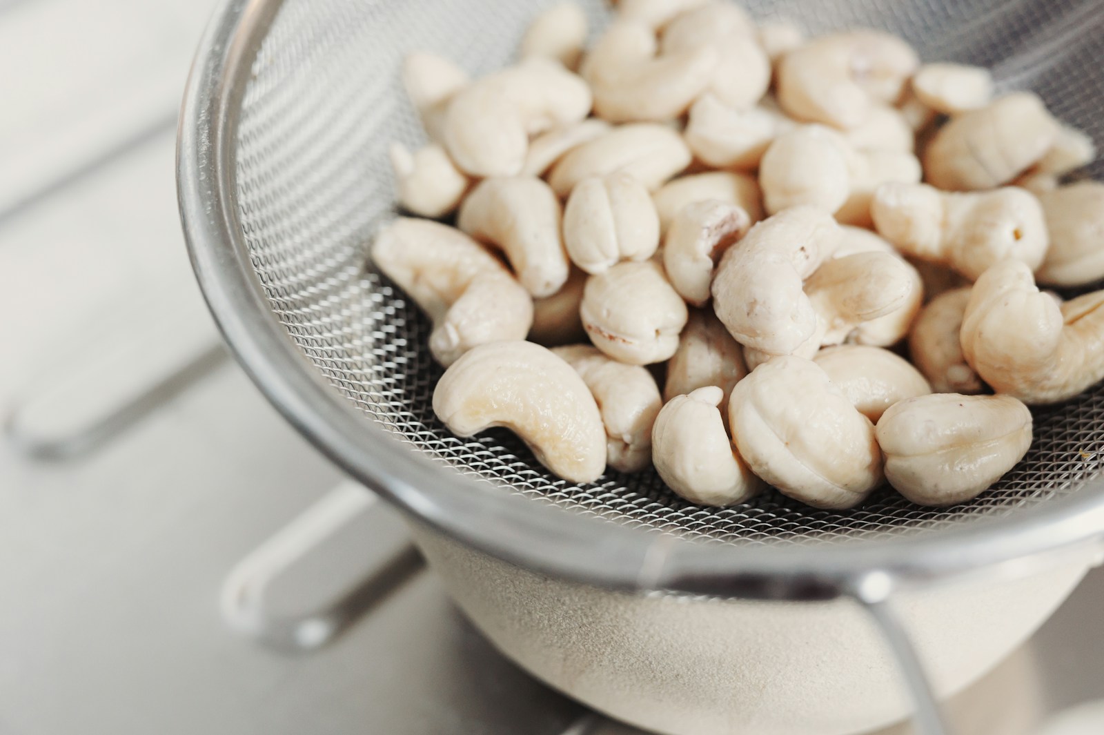 Cashew kernels resting in a metal strainer