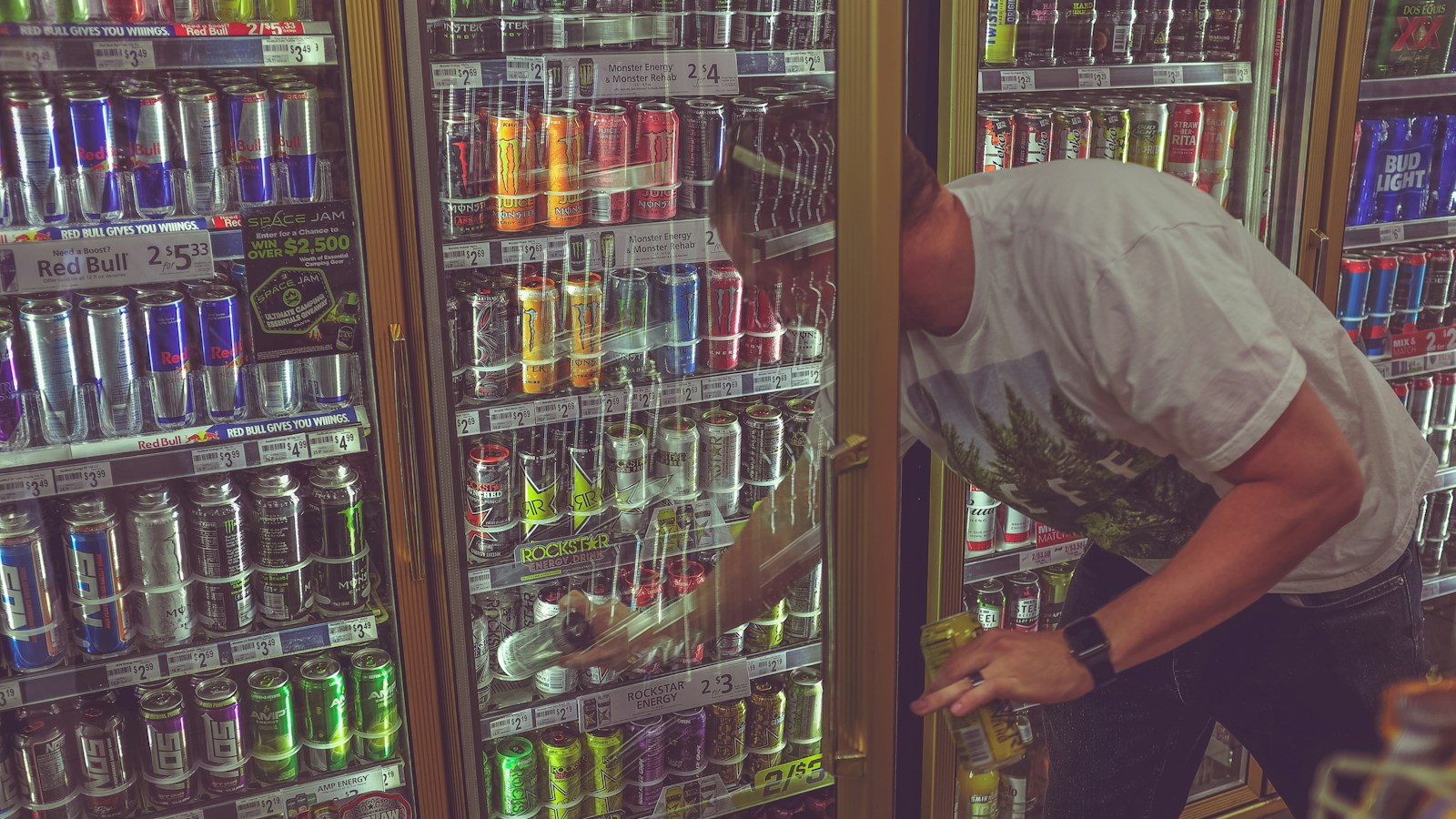 Person reaching for a canned drink in a beverage cooler