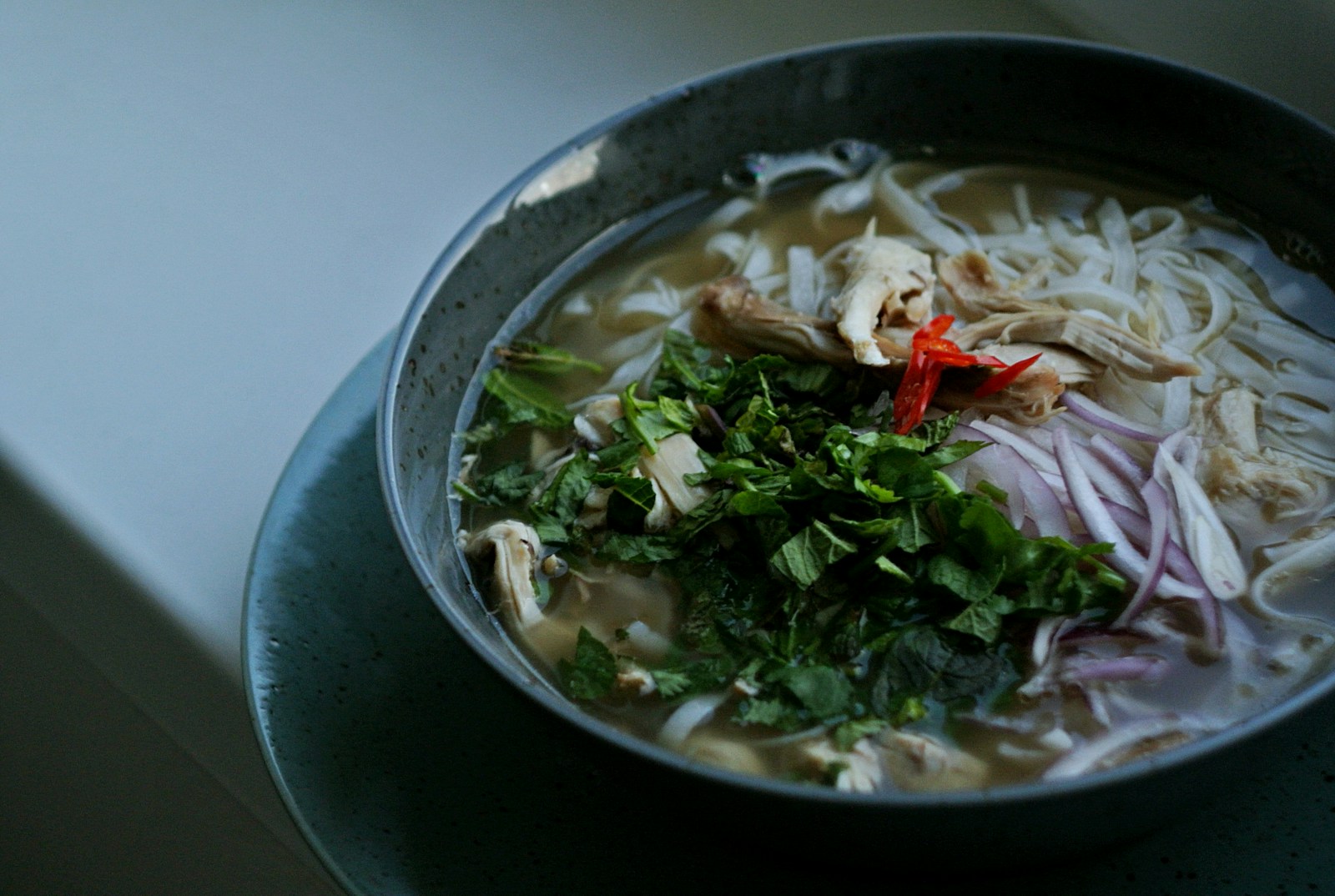 Pho bowl topped with colorful herbs and garnishes