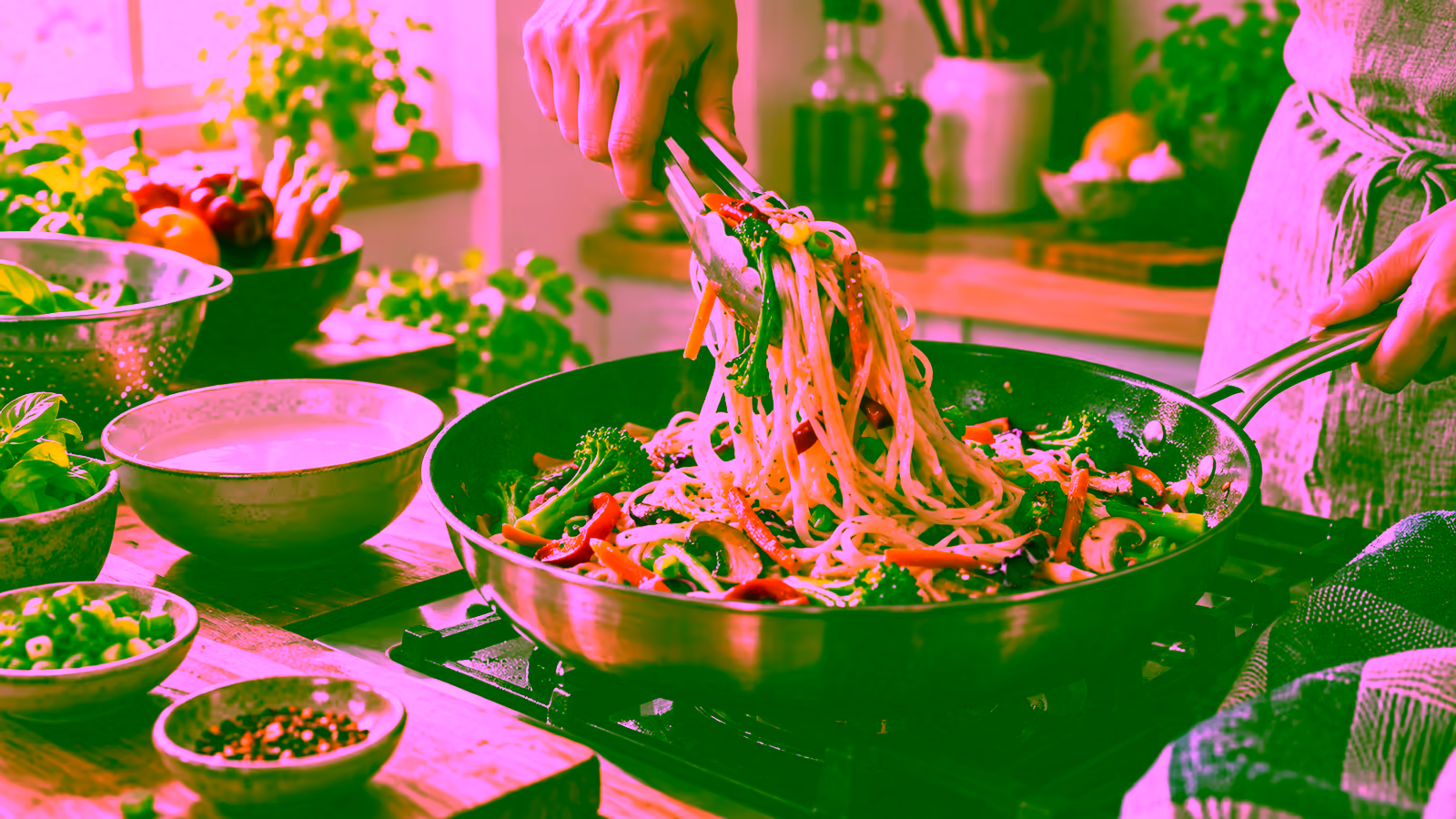 Gluten-free noodles being tossed with vegetables and sauce in a bright home kitchen