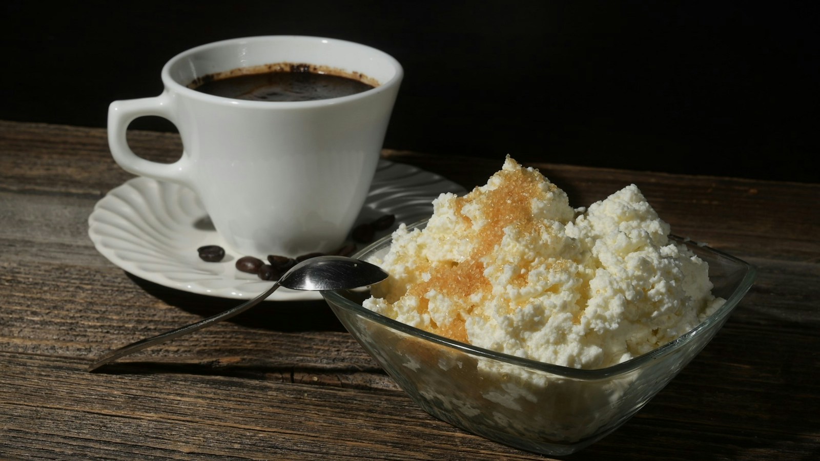 Bowl of cottage cheese beside a cup of coffee