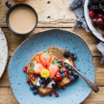 Golden French toast topped with berries on a breakfast table