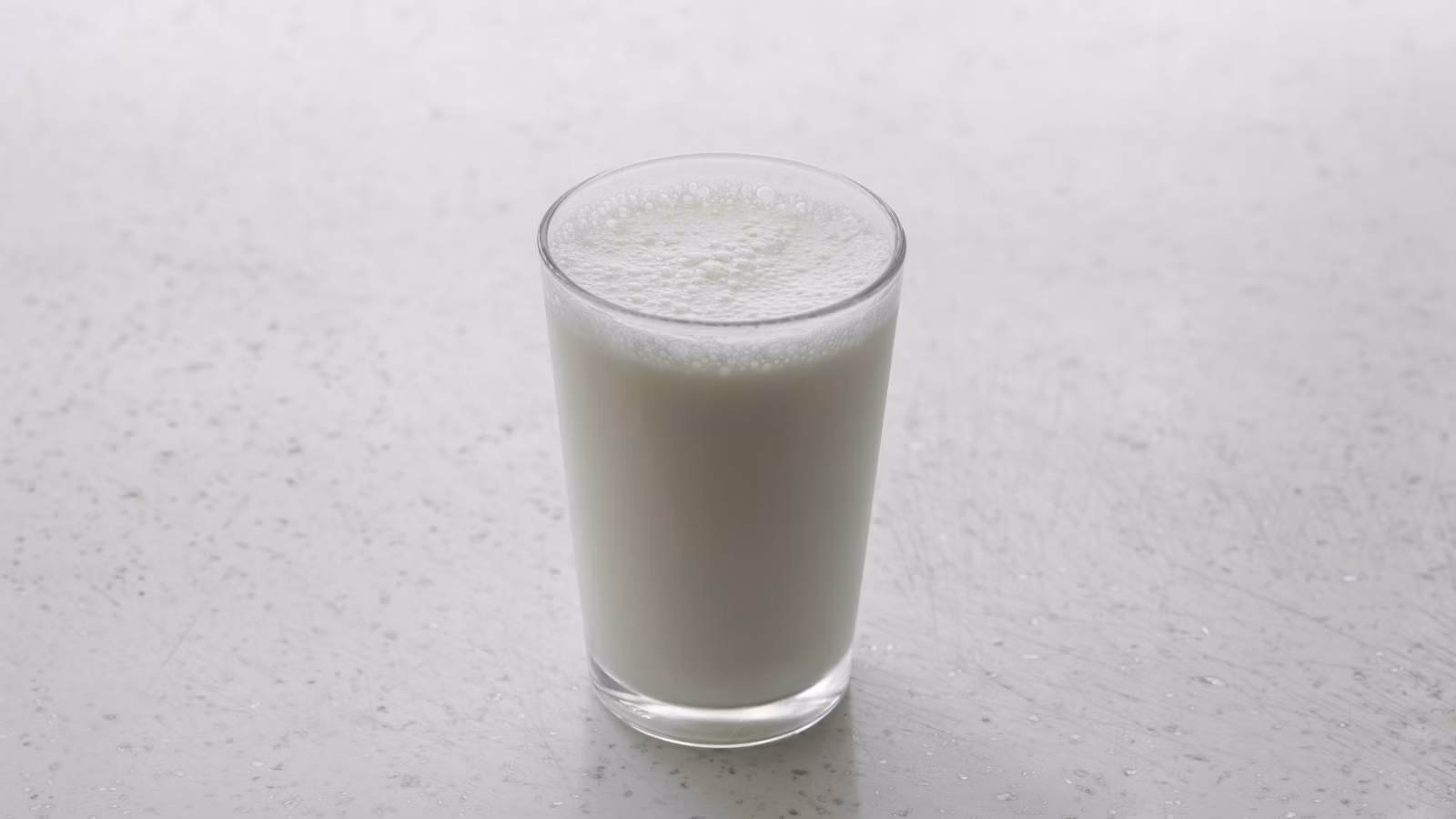 A clear glass filled with cold milk