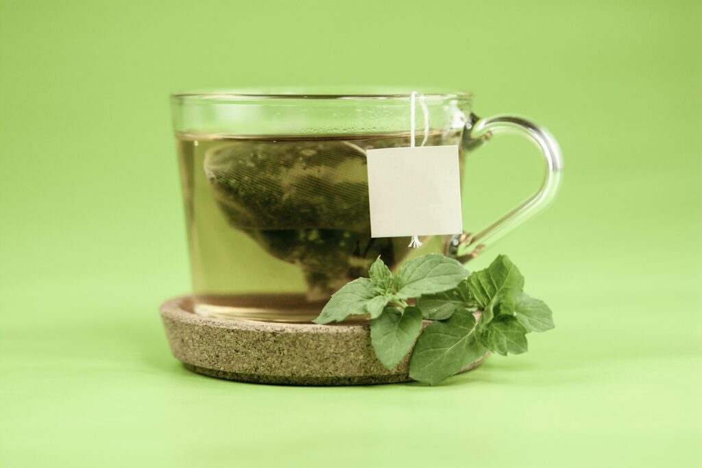 Cup of decaf green tea with fresh green leaves