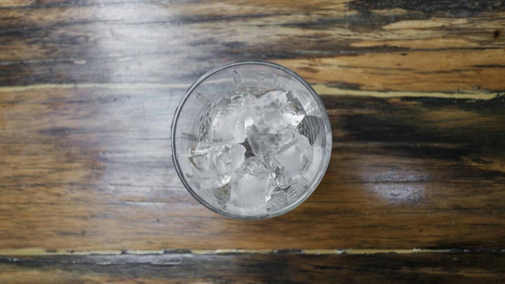 Glass of dark cola with ice on a wooden table