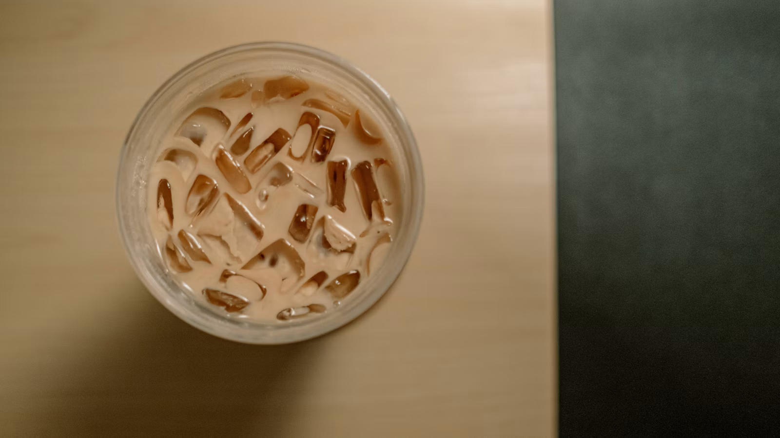 Iced latte in a clear glass with a foamy top