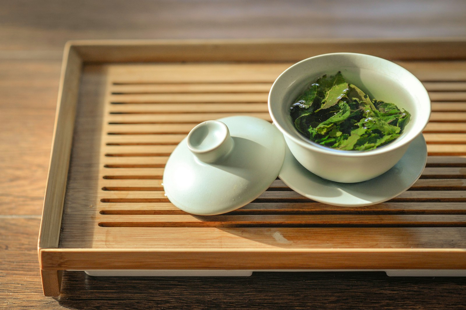 Loose green tea leaves in a ceramic bowl