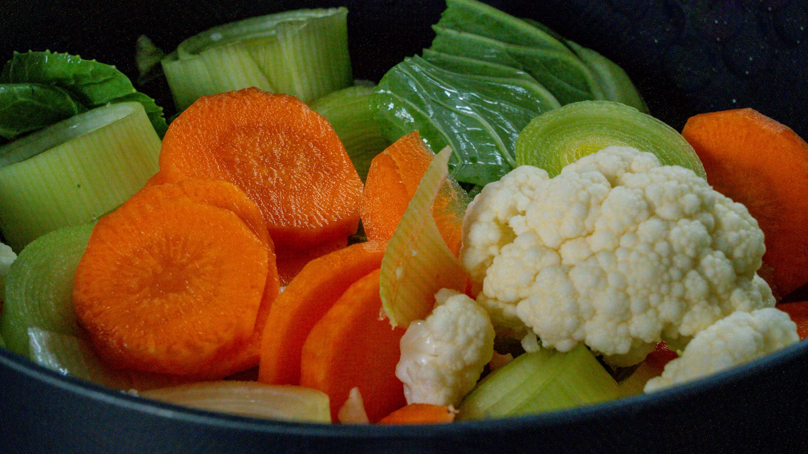 Prepared carrots and other vegetables ready to cook in a stockpot
