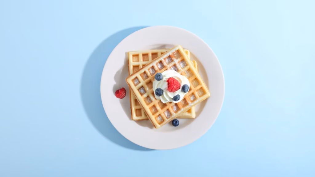 Waffles topped with berries and cream on a plate