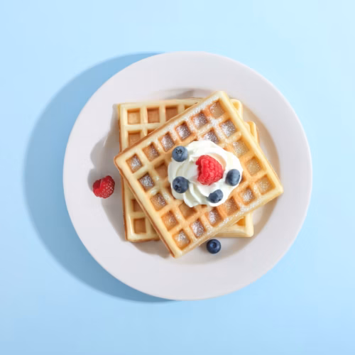 Waffles topped with berries and cream on a plate