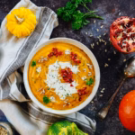 Pumpkin coconut soup in a bowl with a creamy swirl, pumpkin seeds, and pomegranate