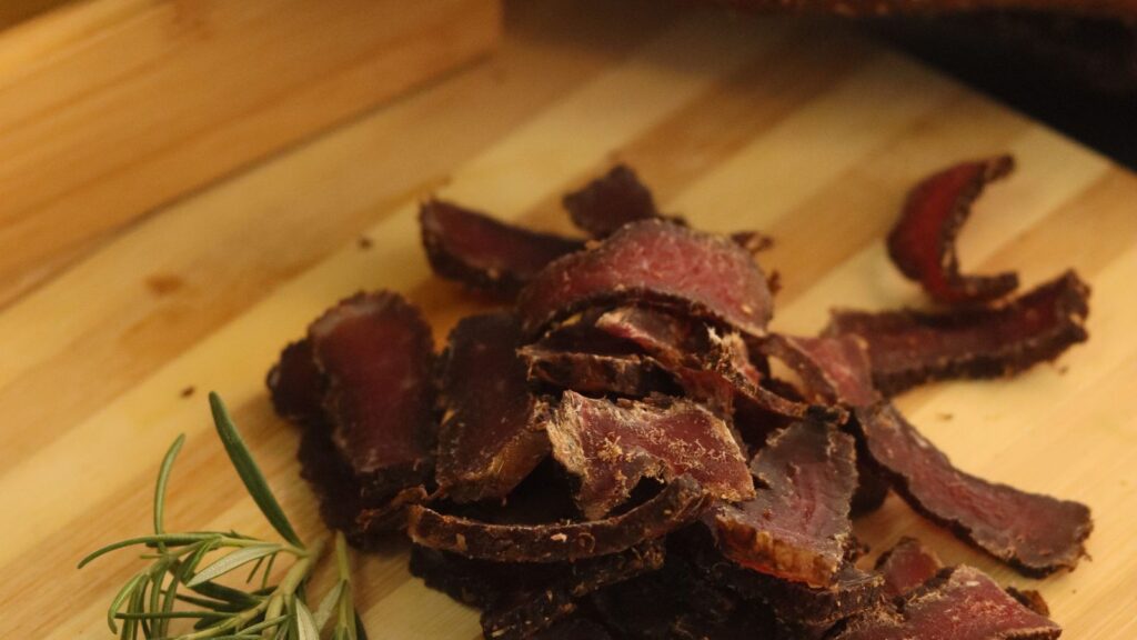 Sliced biltong with rosemary on a wooden board