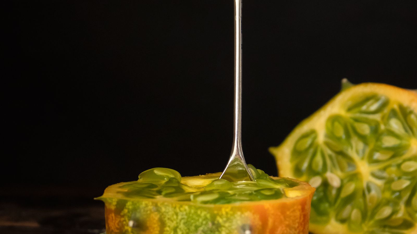 Cut horned melon beside a spoon