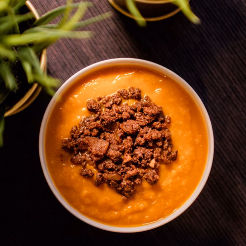 Smooth orange puree served in a white bowl