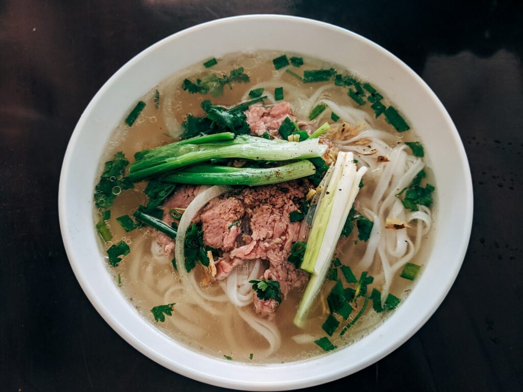 Bowl of Vietnamese pho with rice noodles, broth, and herbs