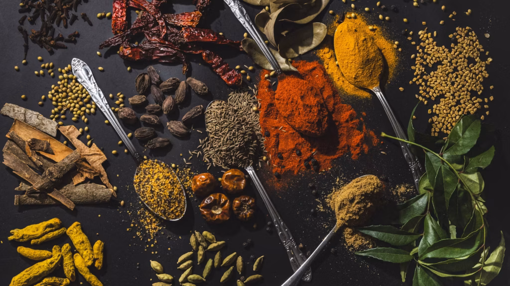 Ground spices arranged in bowls with whole aromatics