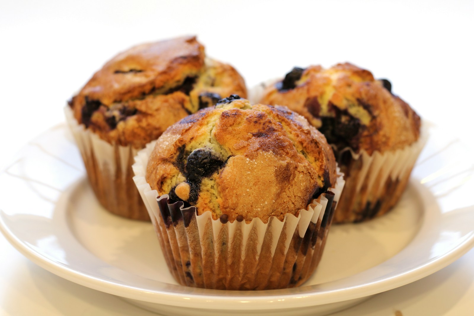 Blueberry muffins in paper cases on a white plate