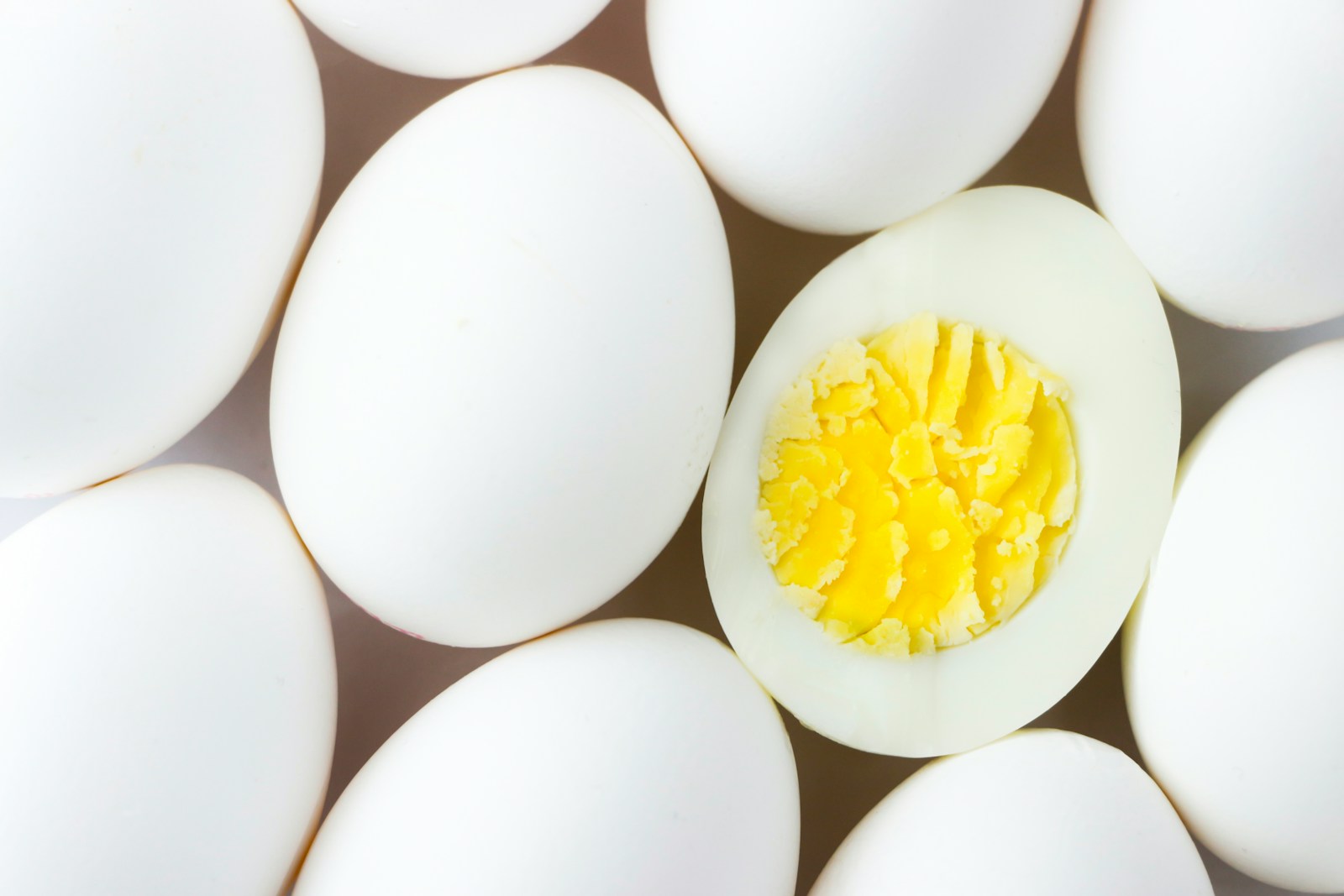 Peeled eggs with one cut open to show the cooked yolk