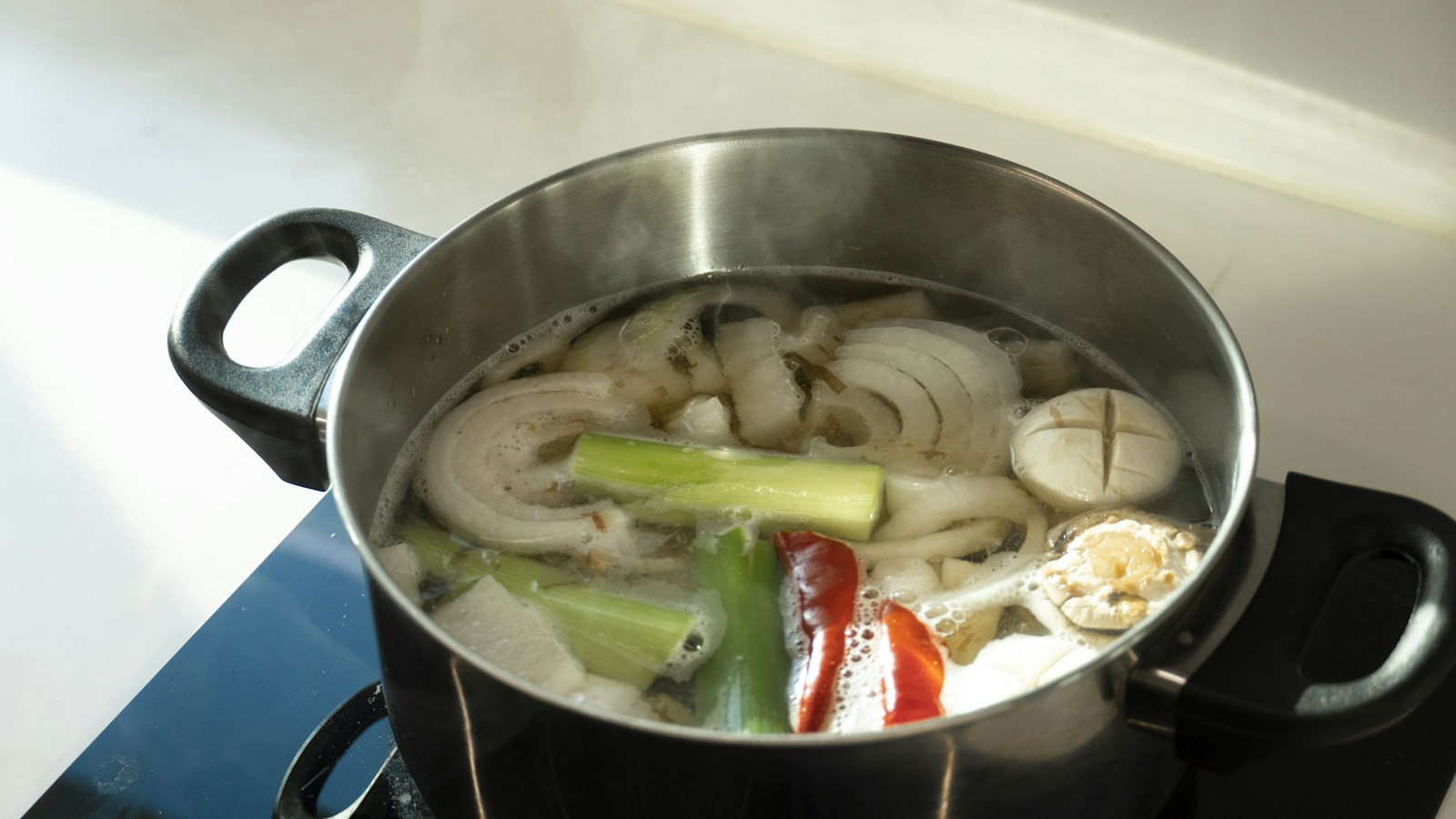 Broth with vegetables simmering in a metal pot