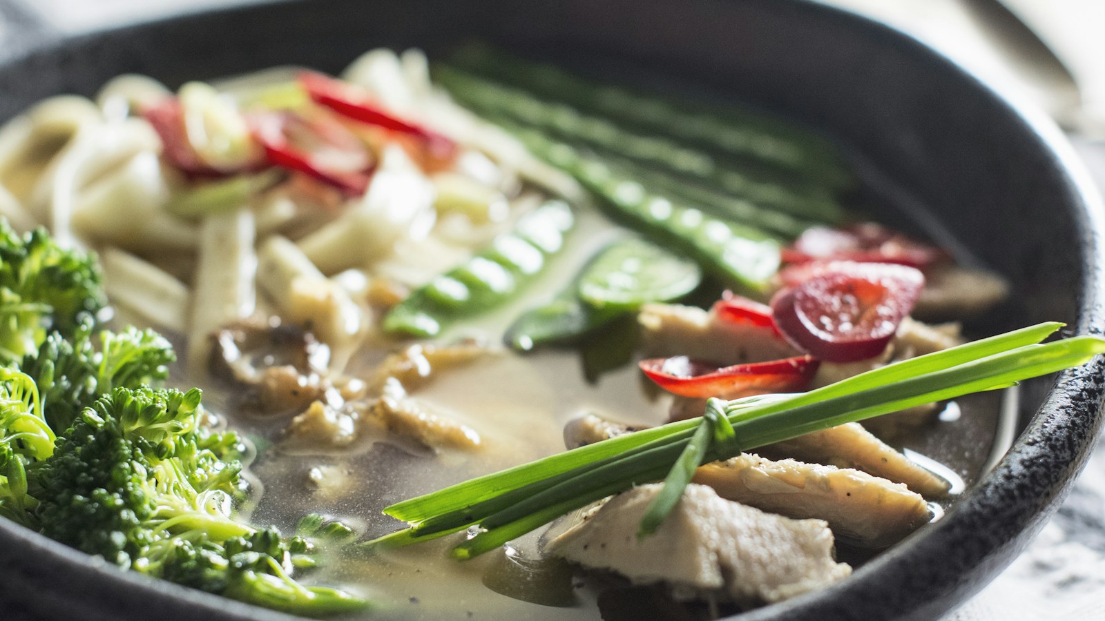 A bowl of noodle soup with vegetables and meat