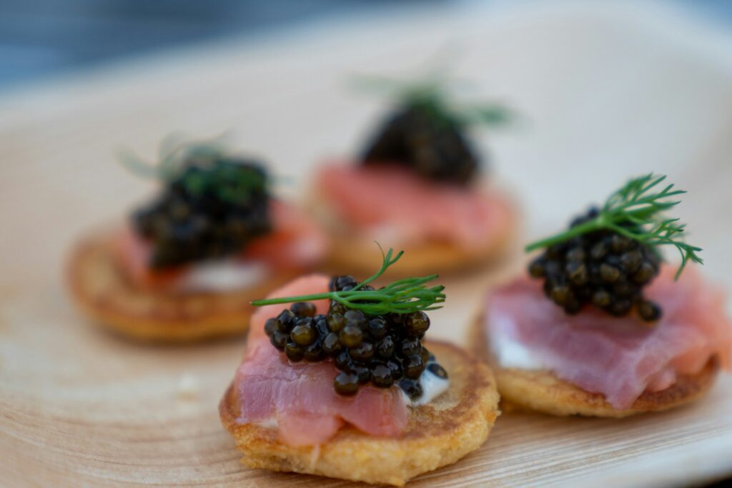 Small canapés topped with dark roe and fresh herbs