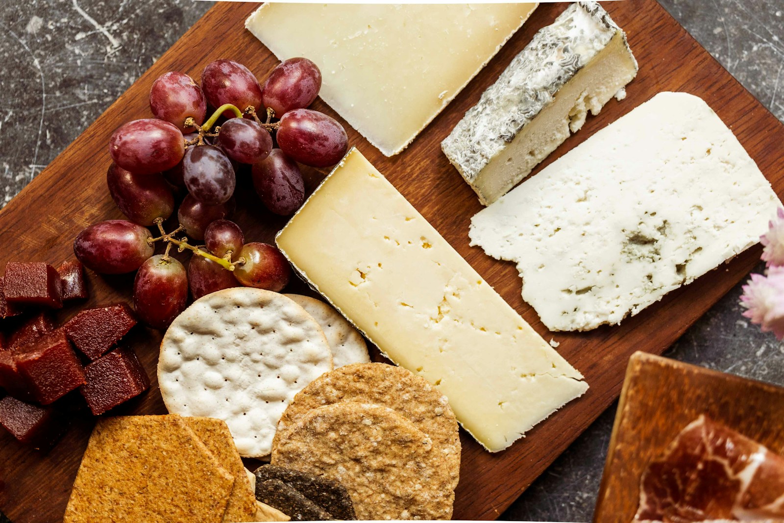 A cheese board with grapes, crackers, and several cheese varieties