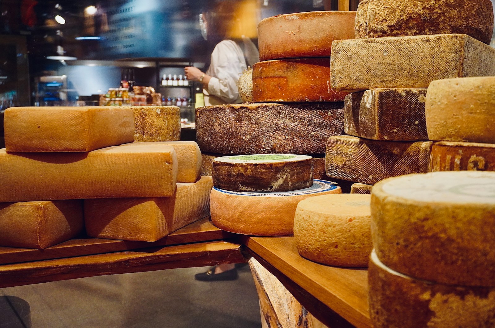 Assorted cheese wheels stacked at a cheese counter