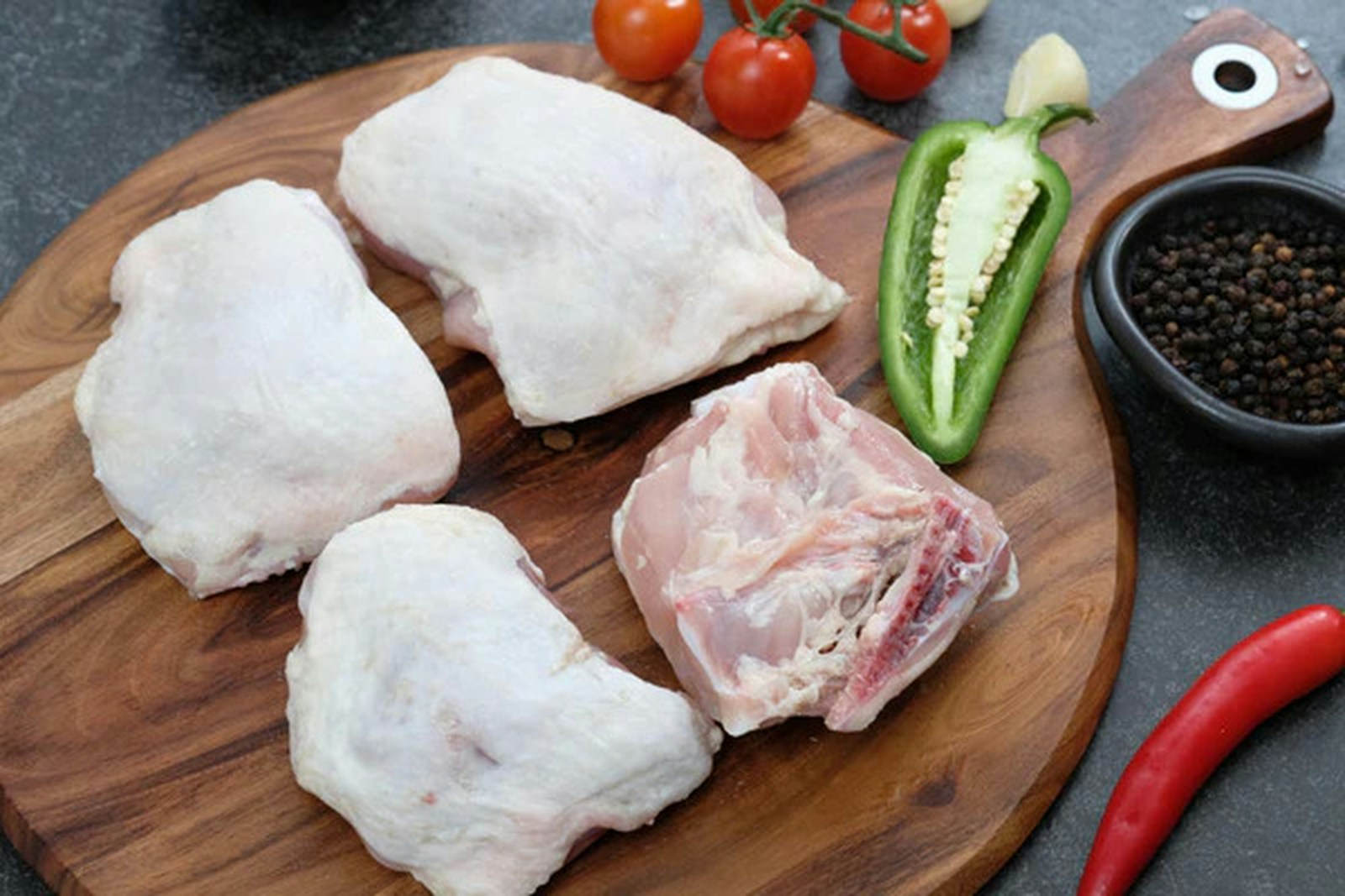 Raw chicken thighs with skin on a cutting board