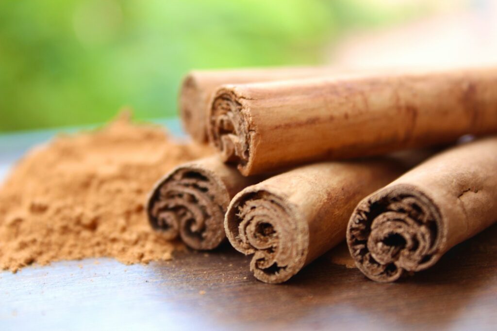 Layered cinnamon sticks beside a mound of ground cinnamon