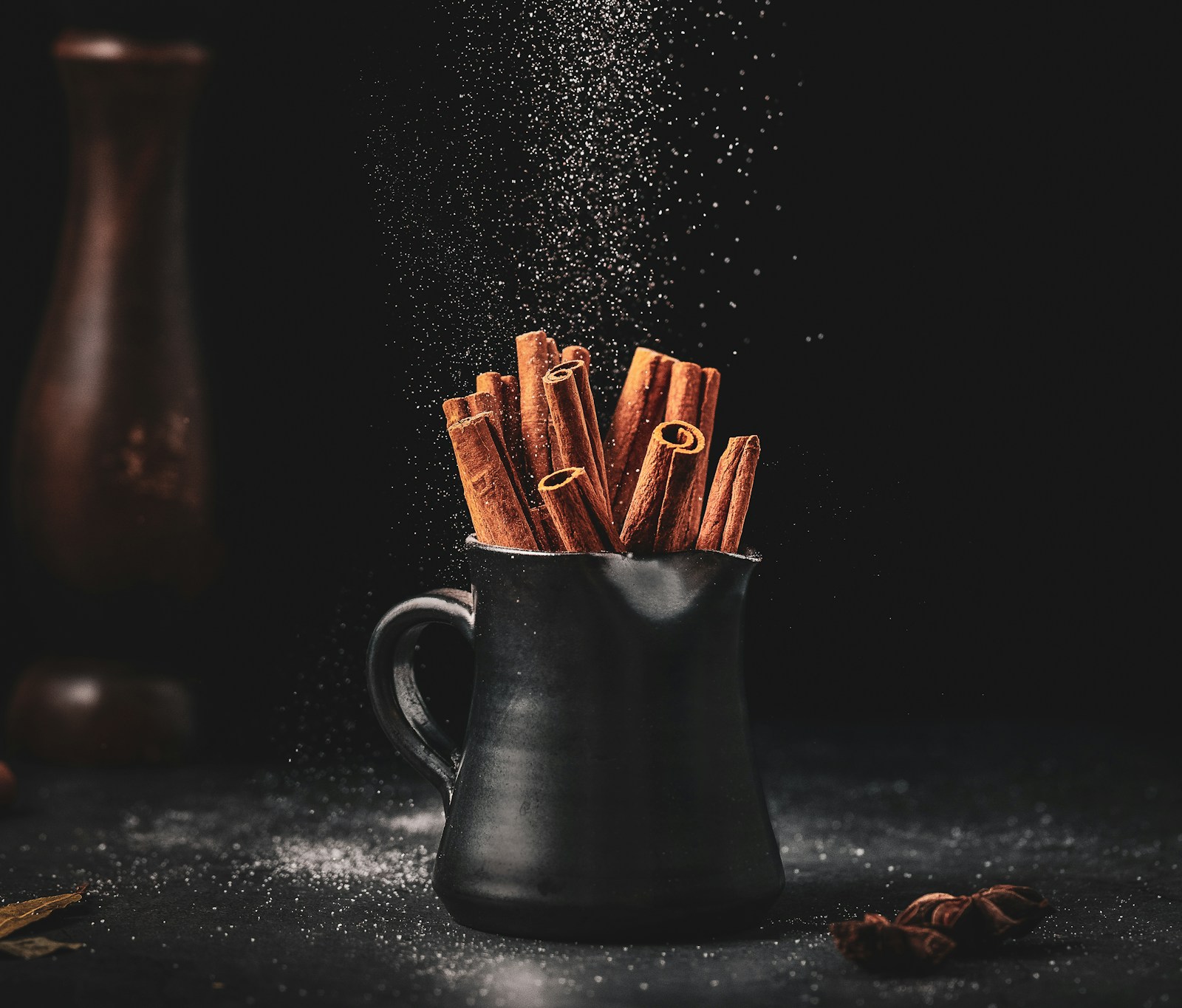Cinnamon sticks standing in a dark ceramic pitcher