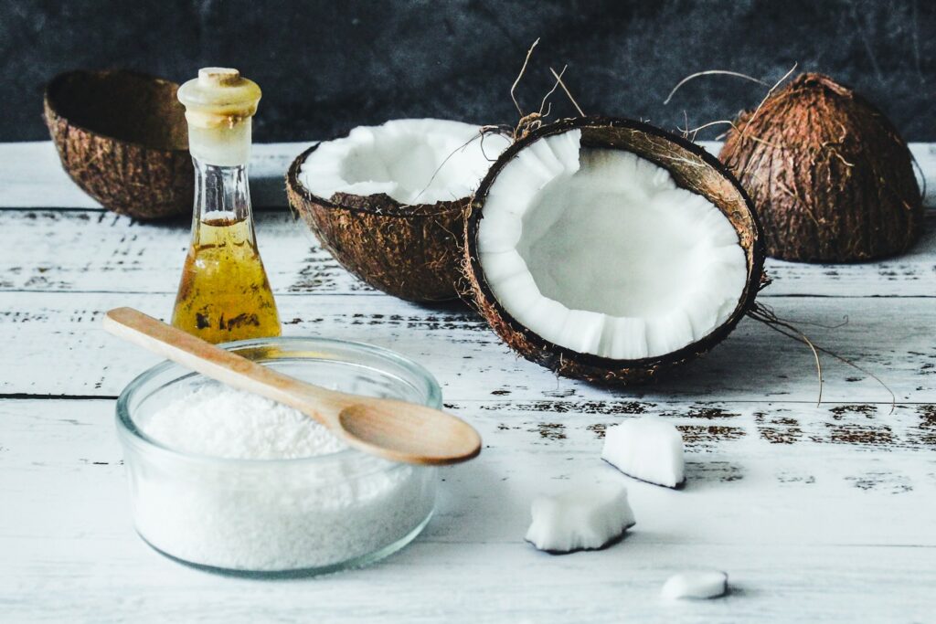 Coconut halves, shredded coconut, and a small bottle of oil