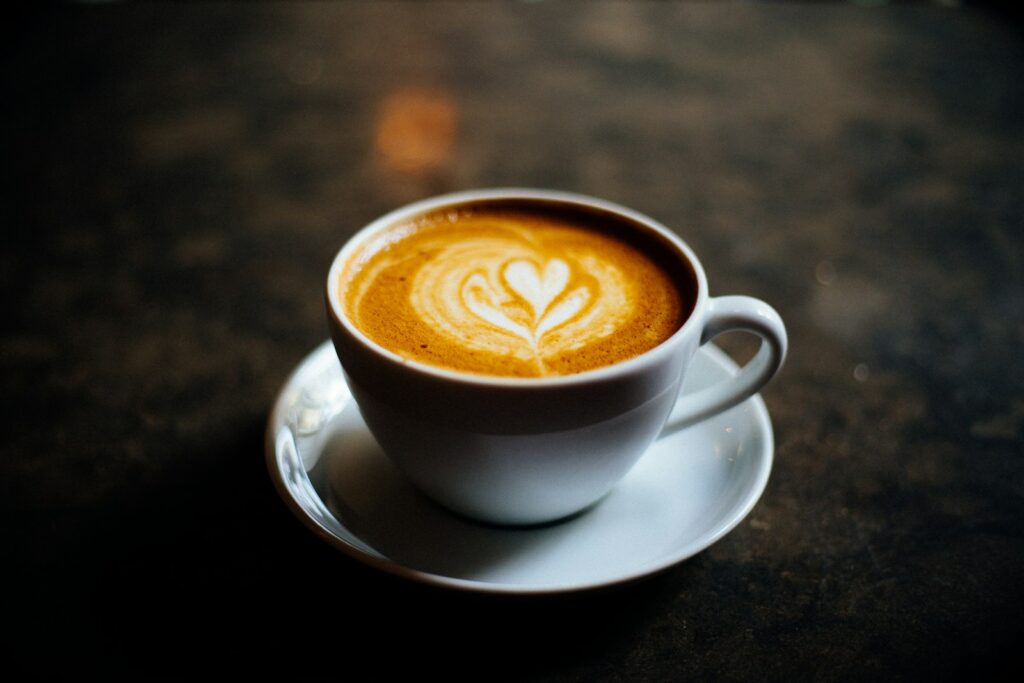 A cup of coffee with milk and a leaf-shaped foam pattern