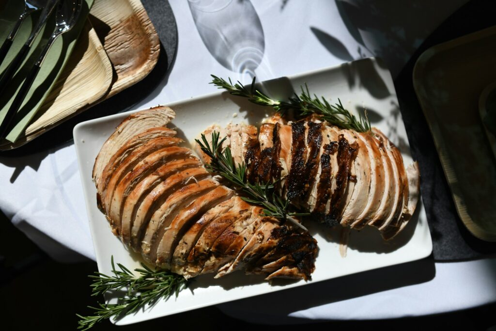 Roasted turkey breast sliced on a platter with rosemary