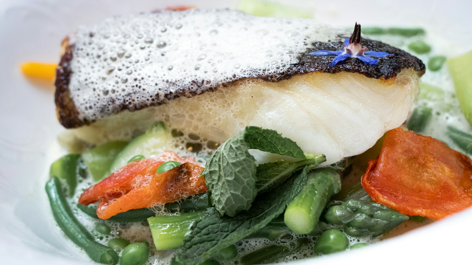 Cooked white fish served over vegetables with a light sauce