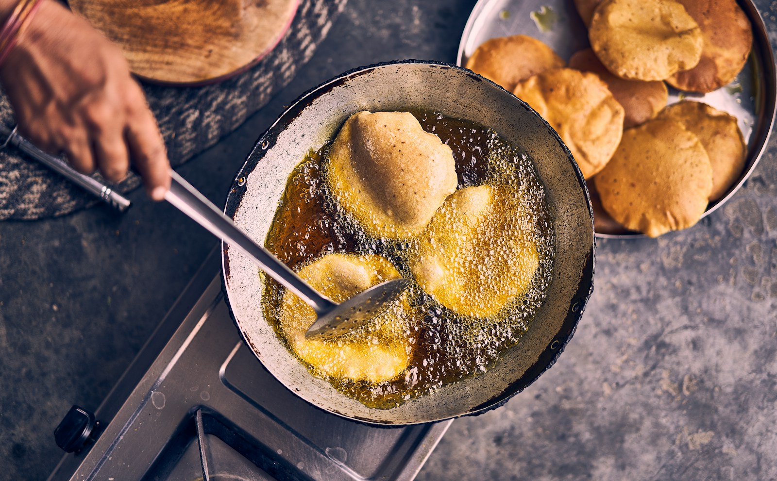 Flatbreads frying in a pan of hot oil