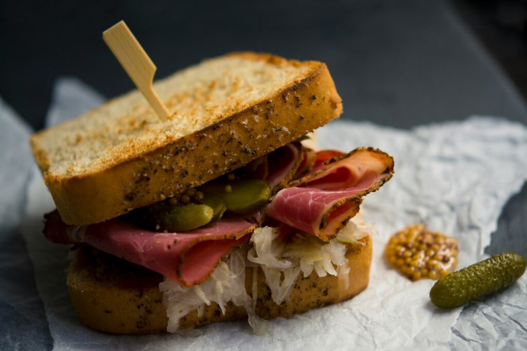 Cured beef sandwich with sauerkraut, mustard, and a pickle