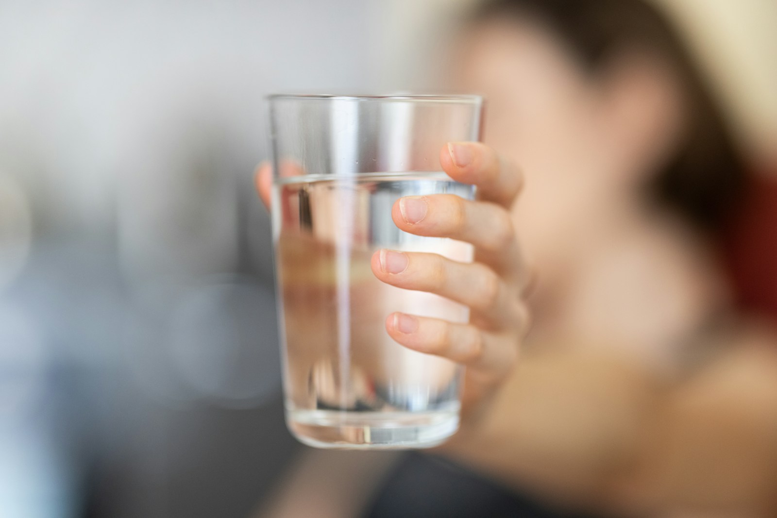 A clear glass of water held in one hand
