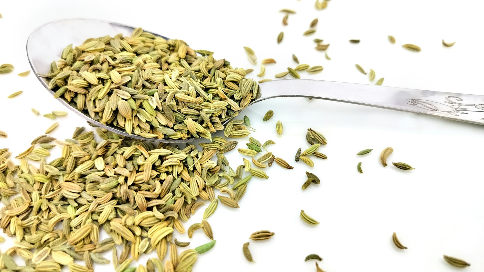 Green fennel seeds on a metal spoon