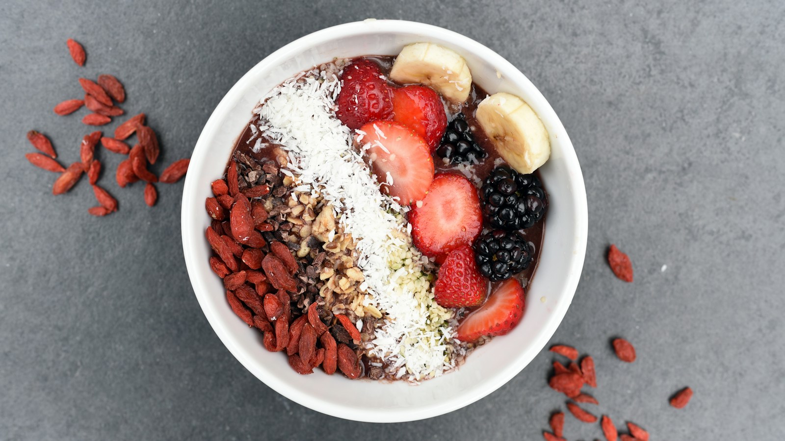 A smoothie bowl topped with berries, banana, coconut, and other toppings