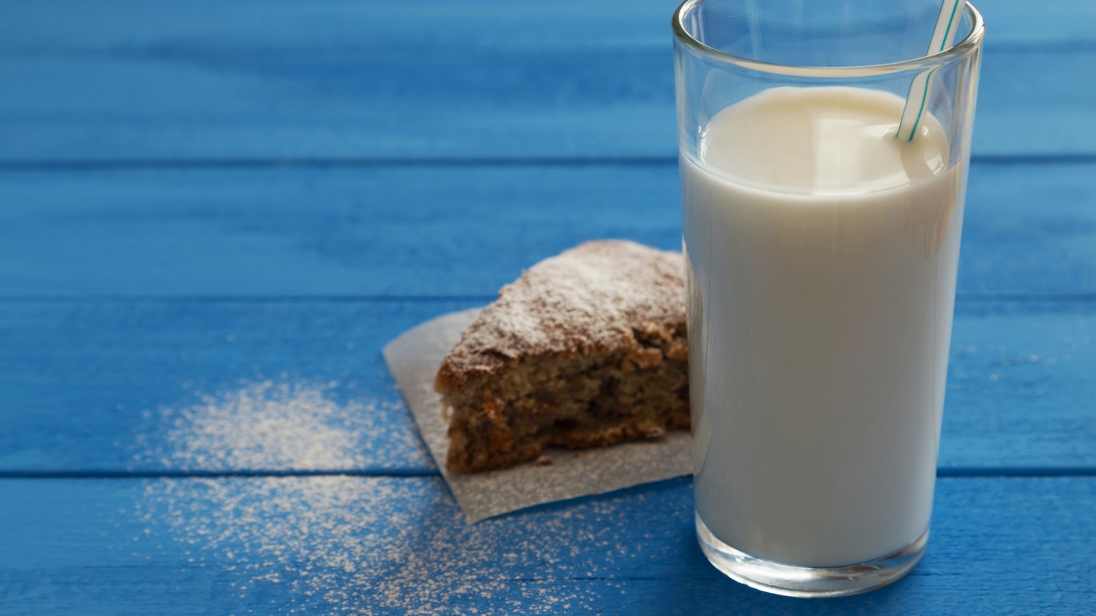 A glass of milk beside a slice of cake
