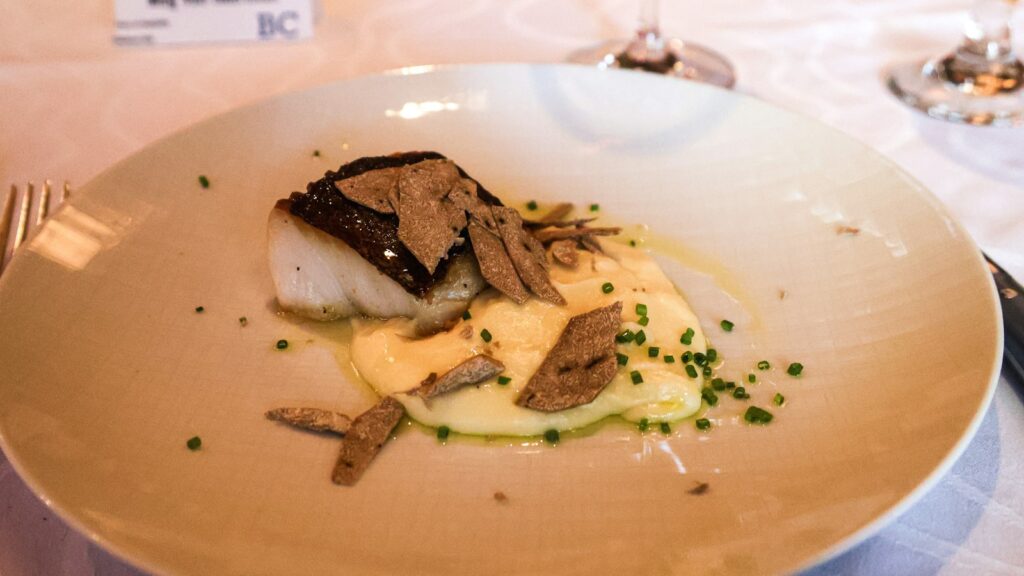 Cooked halibut served with sliced truffles and sauce