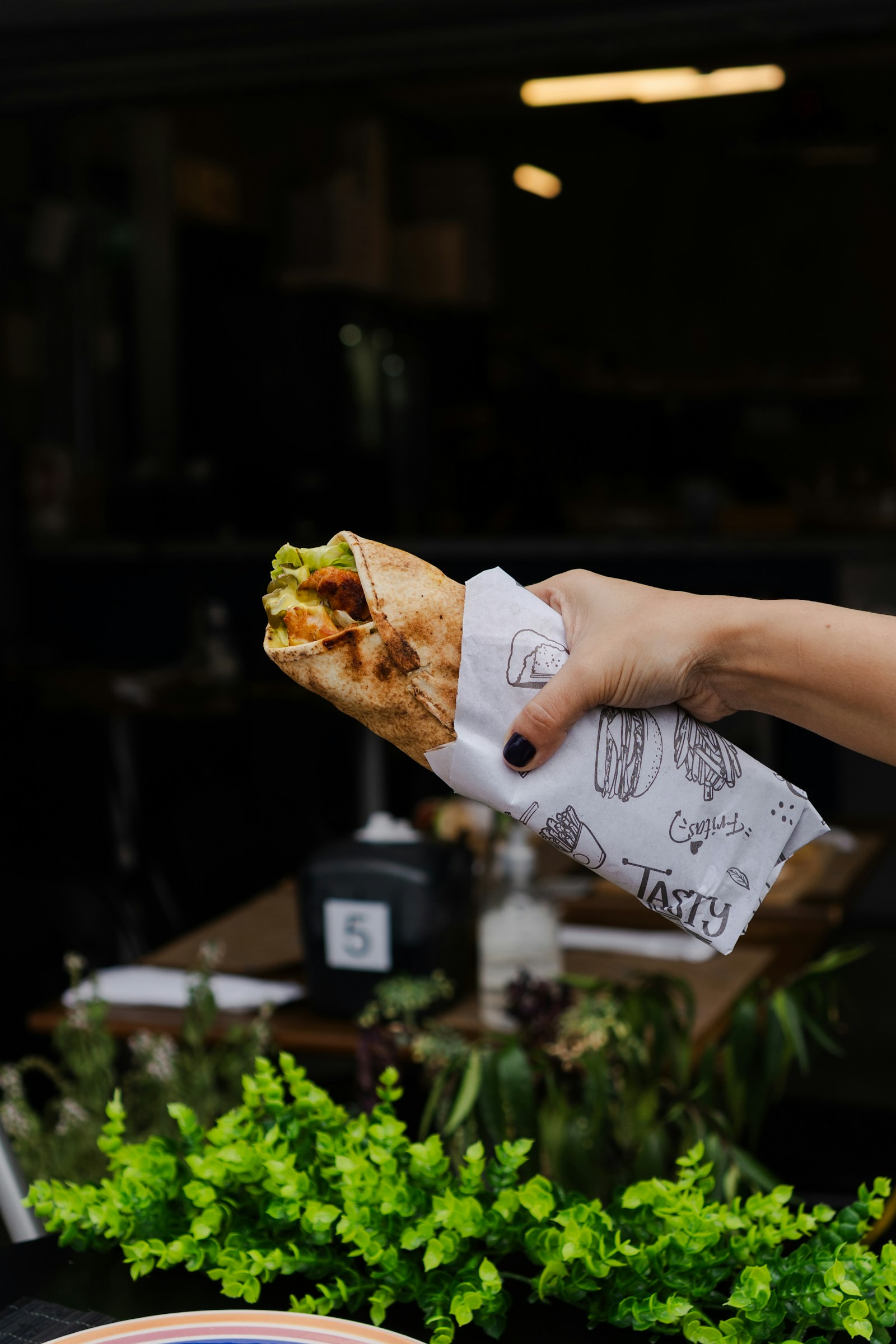 A hand holding a takeaway wrap in paper