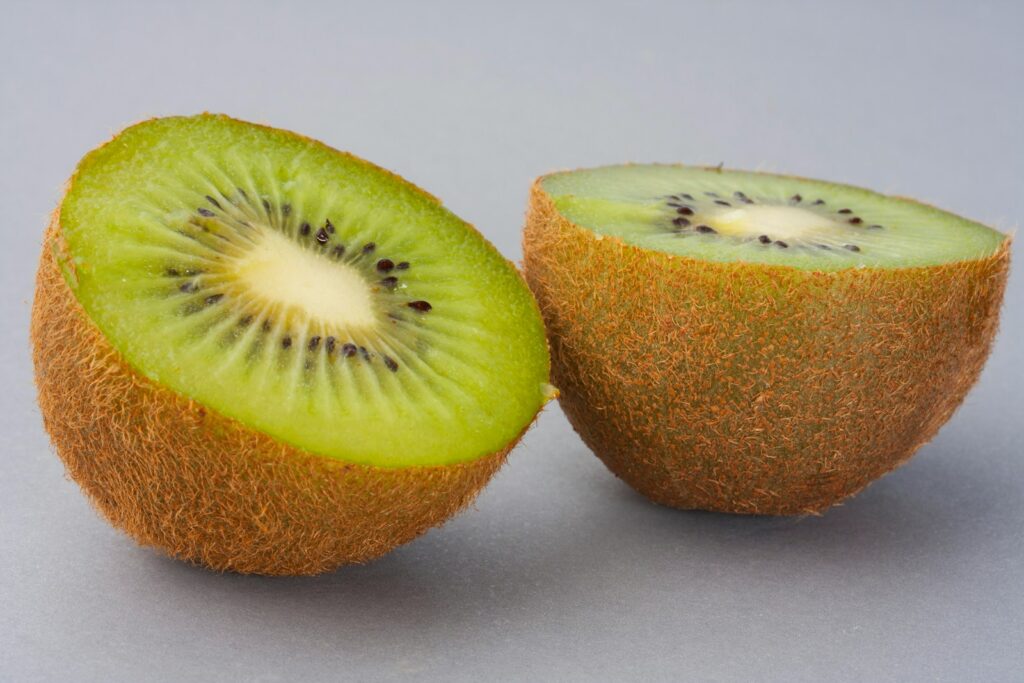 Two kiwi halves with fuzzy brown skin and green flesh