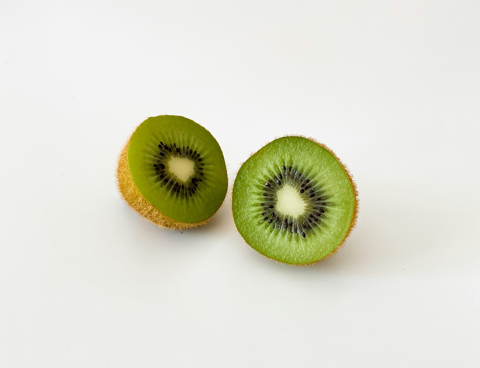 Two green kiwi halves on a white background