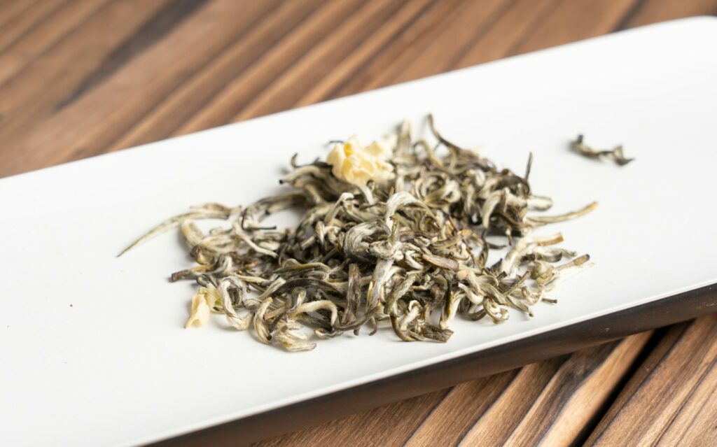 Loose jasmine green tea leaves on a white plate