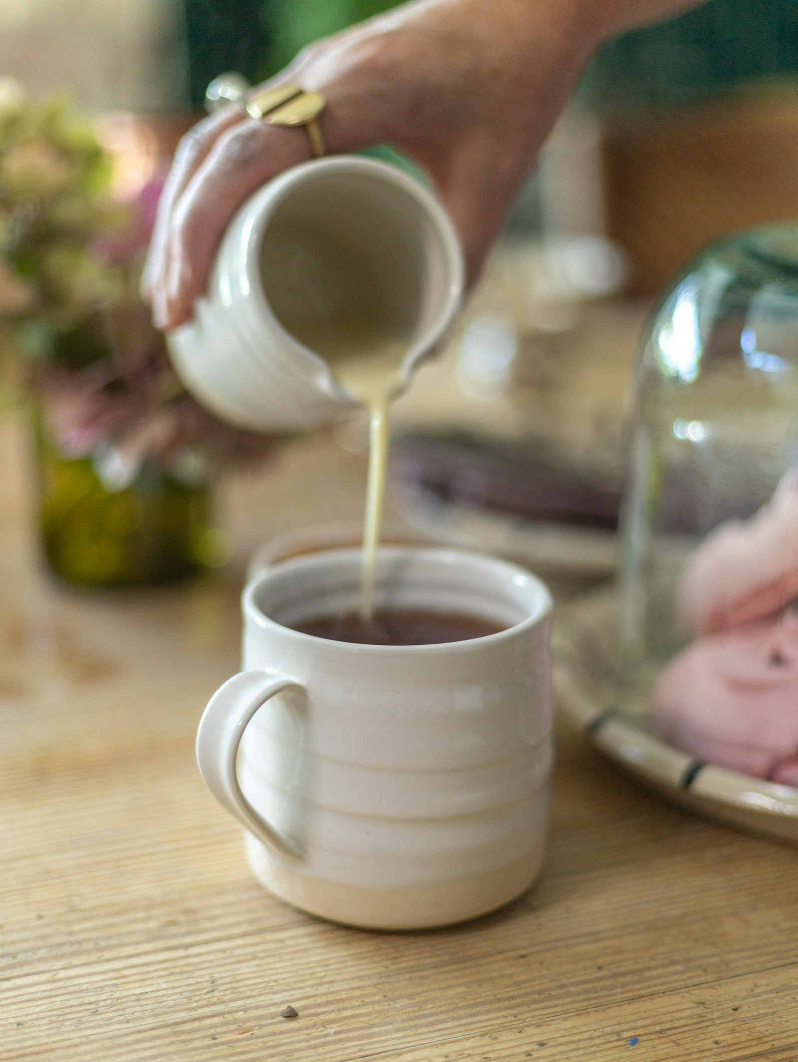 Milk being poured from a small jug into a mug