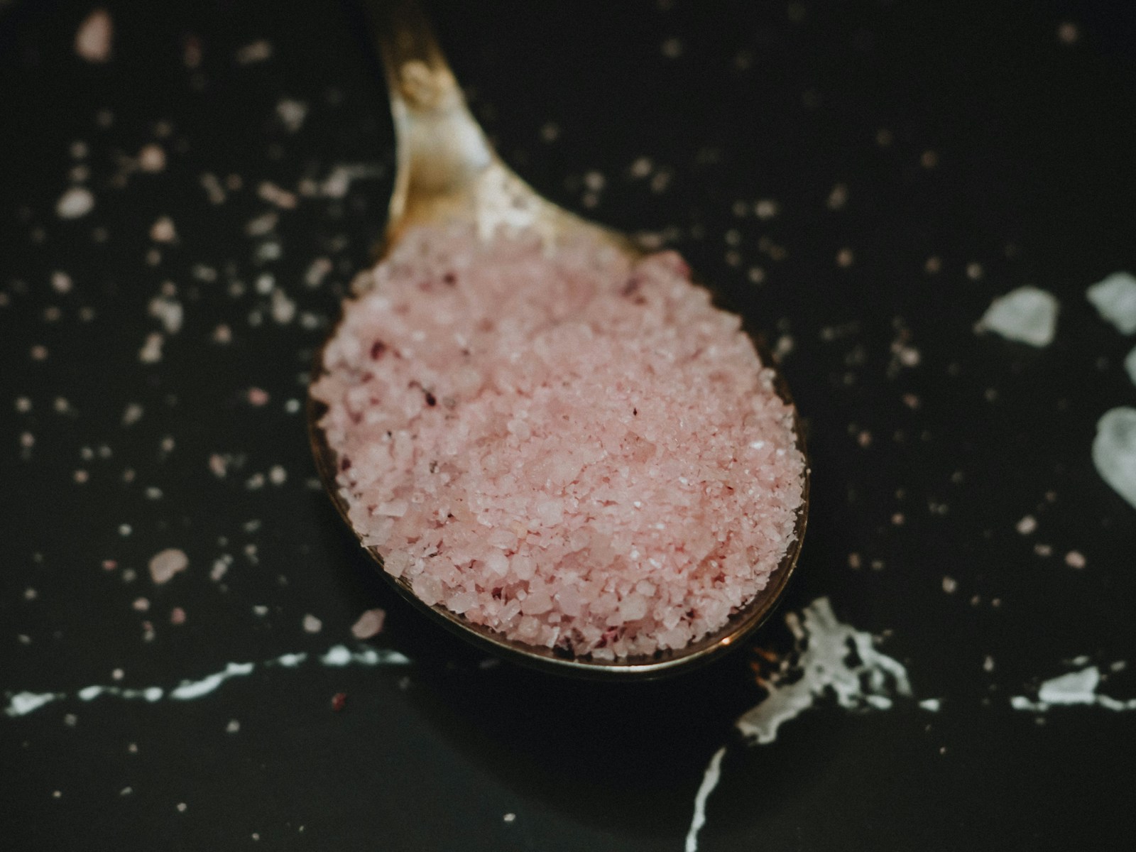 Pink salt crystals in a wooden spoon