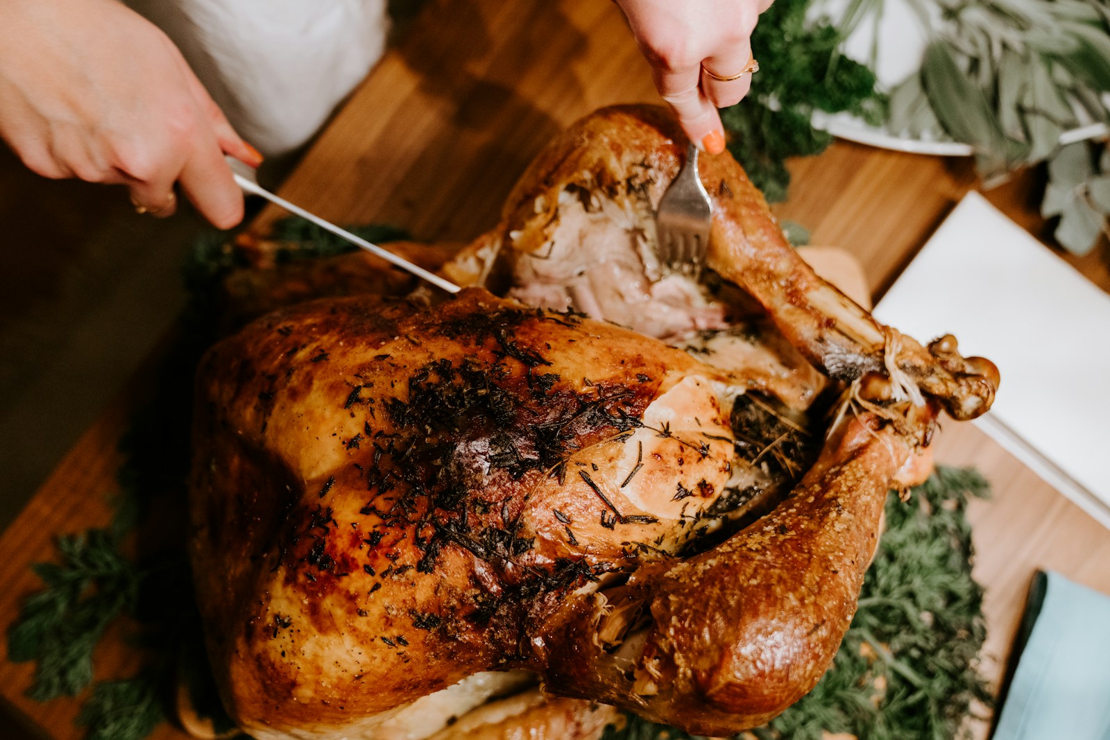 Hands carving a roasted bird on a wooden board
